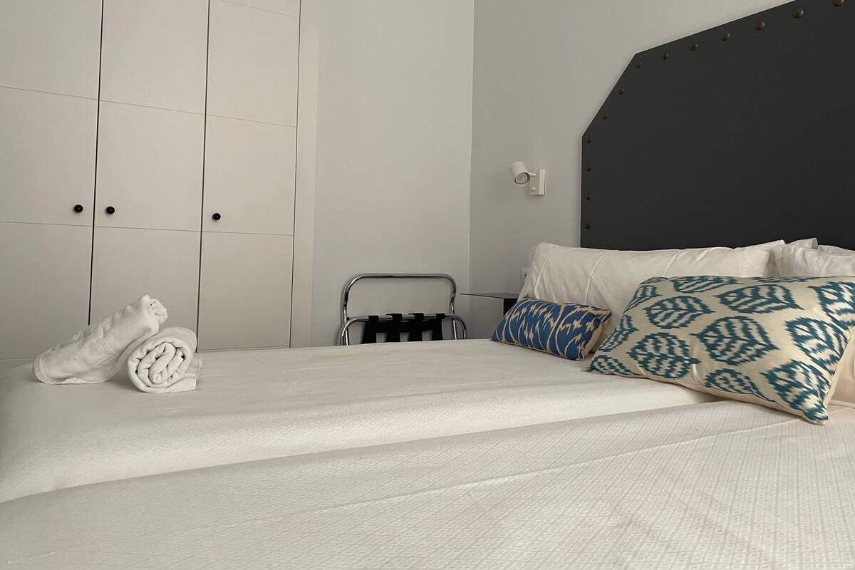 A hotel room with a bed, a chair, and a wardrobe.