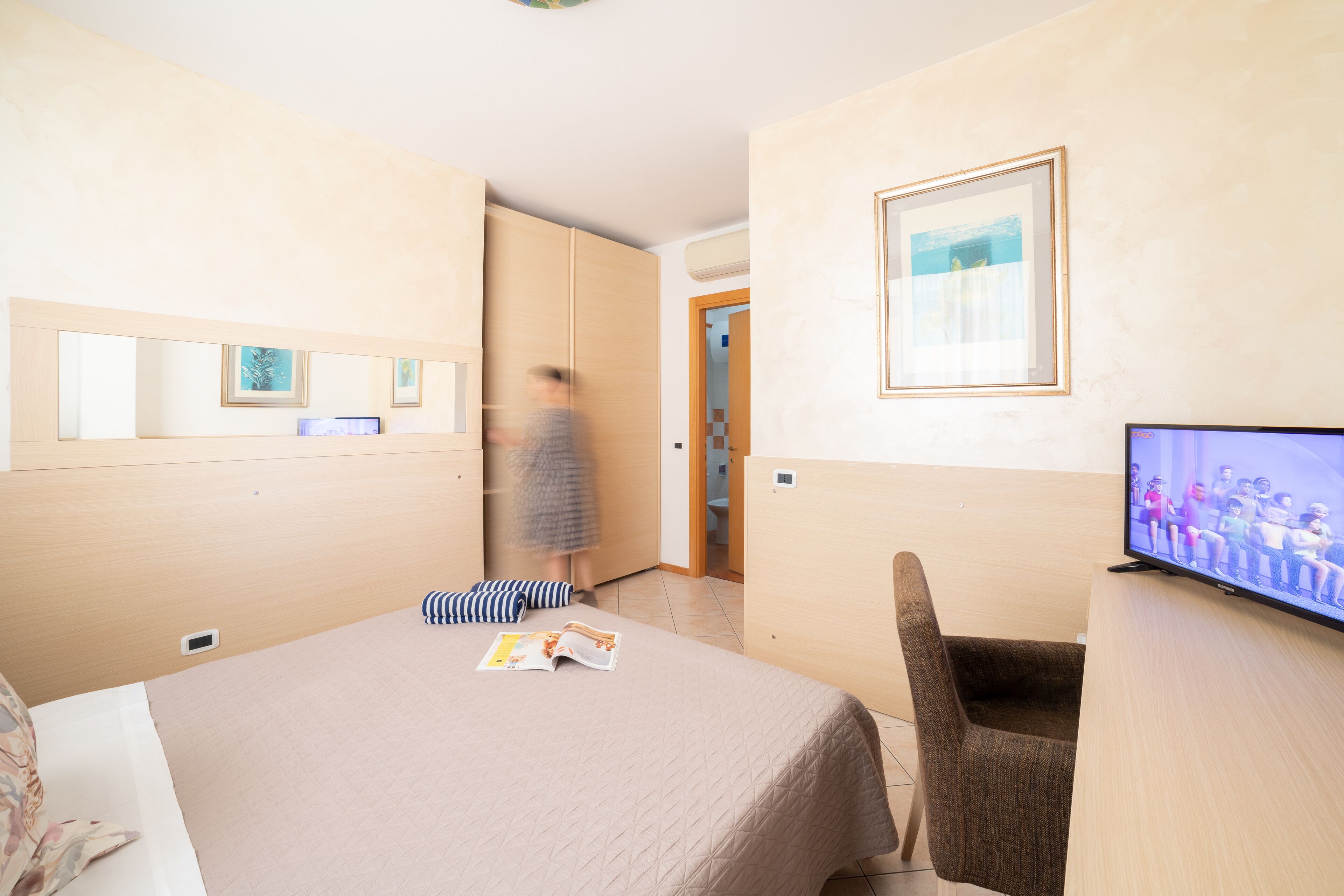 Ein Hotelzimmer mit einem Bett, einem Fernseher, einem Sessel und einer Tür zu einem Badezimmer.