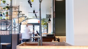 Ein Restaurantinneres mit einer zentralen Sitzgruppe, einem Baum und einer Bar.