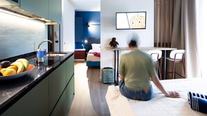Ein modernes Hotelzimmer mit Küchenzeile, einem Esstisch und einem Bett.
