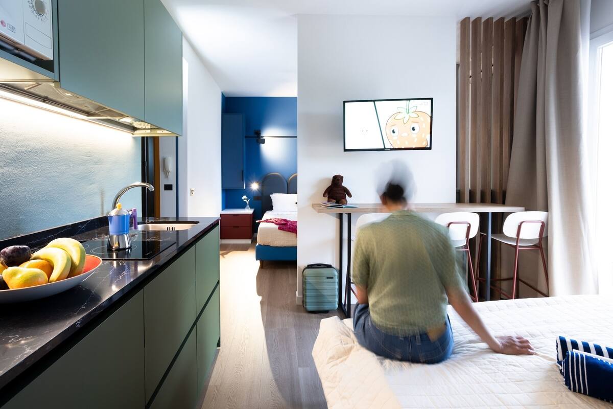 Una camera d'albergo moderna con angolo cottura, un tavolo da pranzo e un letto.