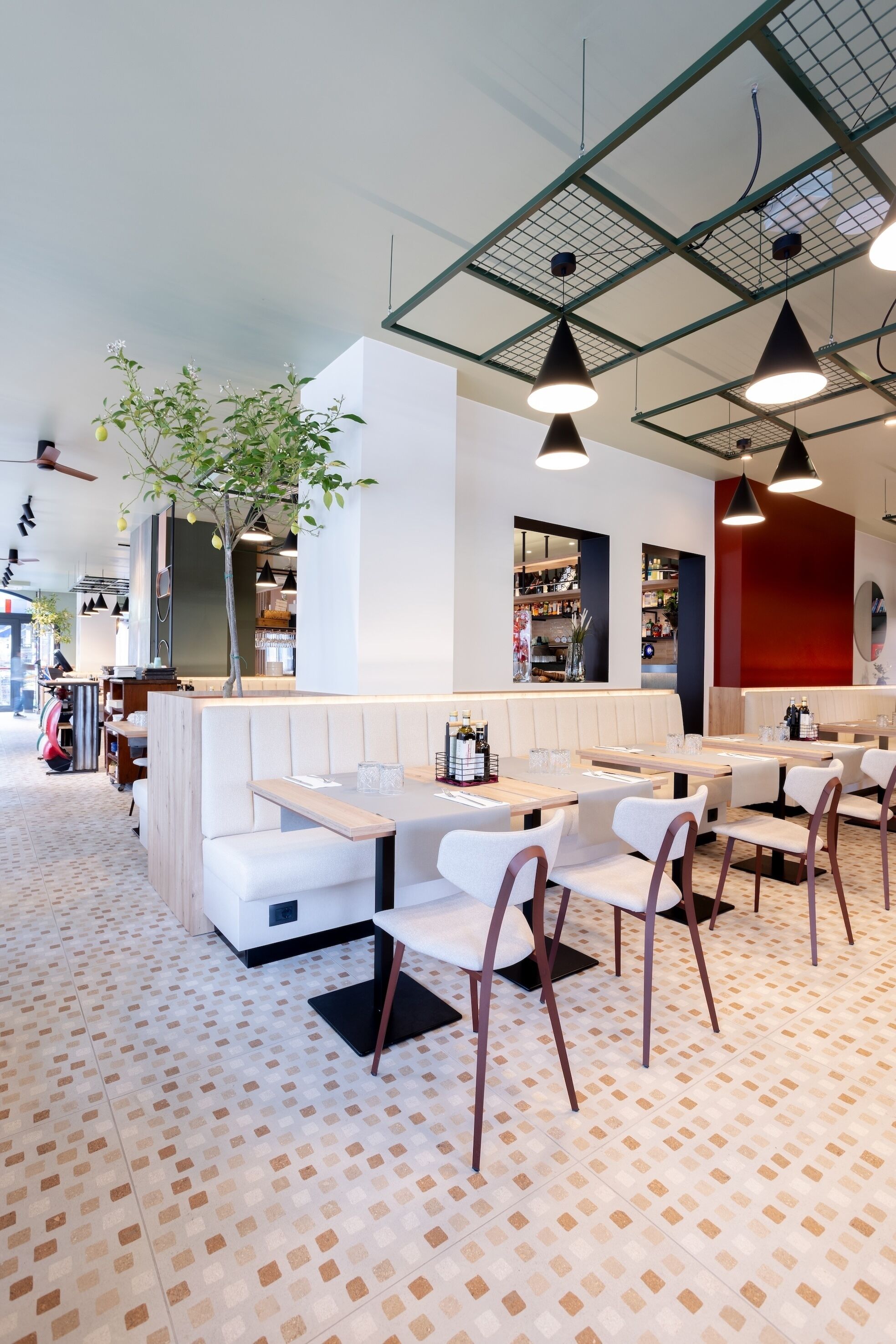 Et moderne restaurantmiljø med båse, borde og hængende lamper.