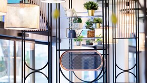 Ein modernes Interieur mit einem Metallregal, das Pflanzen beherbergt, und einem Korbstuhl.