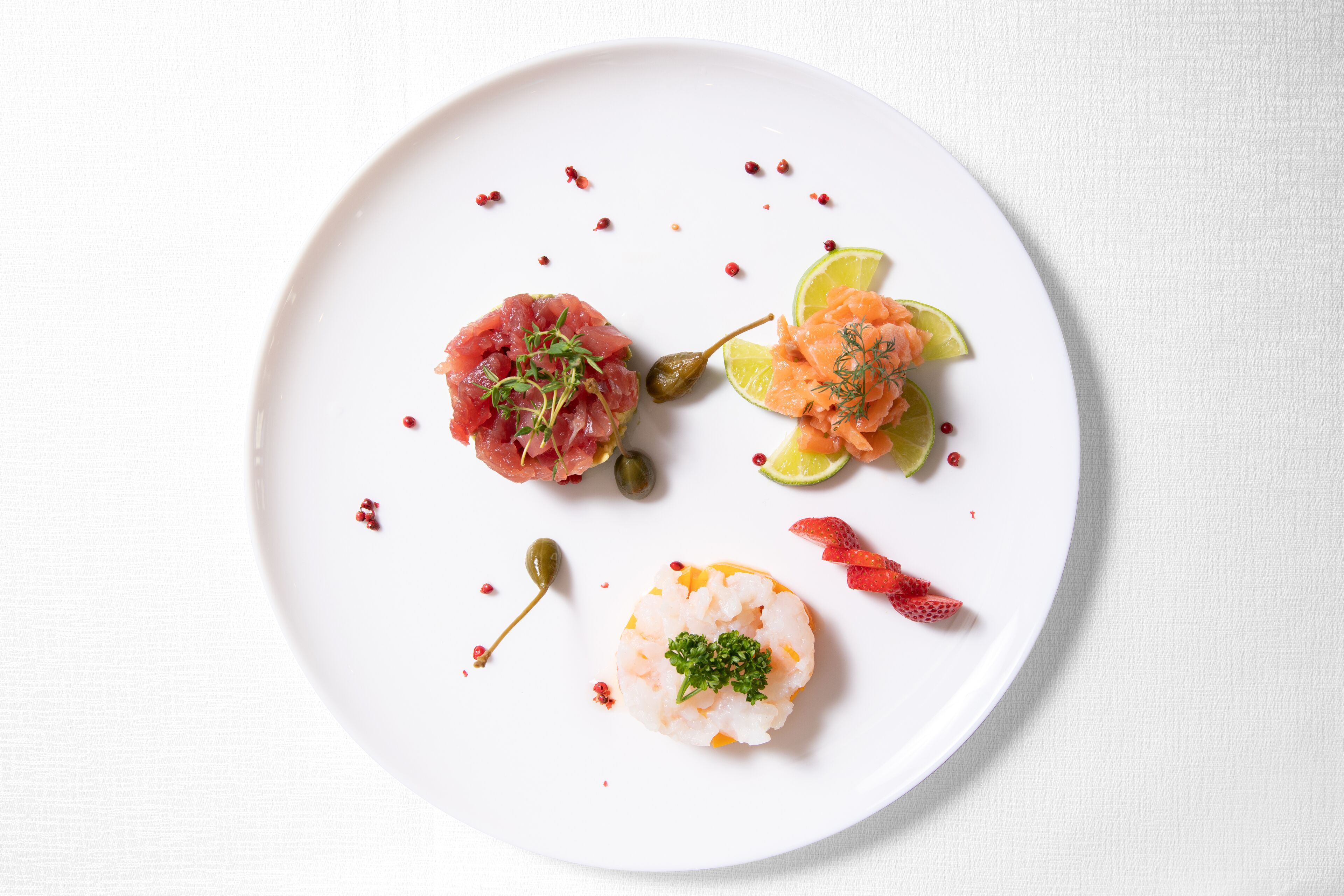 A white plate with three different types of seafood appetizers.