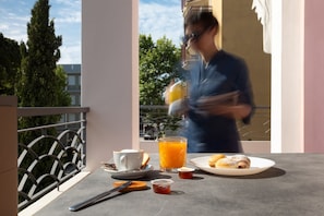 Ein Frühstückstisch mit einer Tasse, einem Glas Orangensaft, einem Teller mit Gebäck und einer kleinen Marmeladendose.