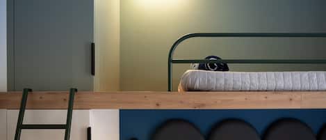 Una cama litera con escalera, cabecera con diseños circulares y dos luces fijadas en la pared.