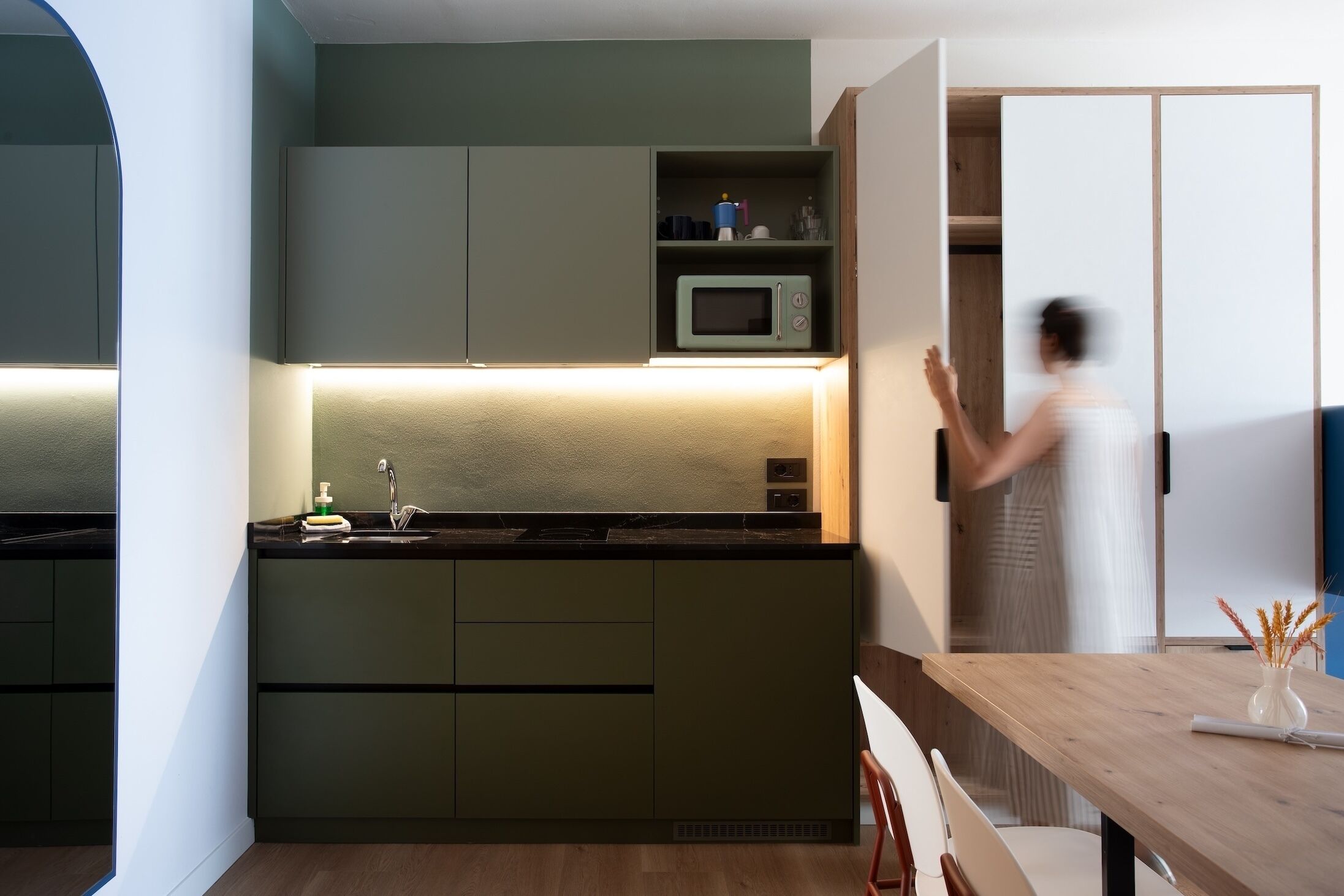 Une cuisine moderne dotée d’appareils électroménagers intégrés, une table à manger en bois et une vue sur la pièce adjacente.
