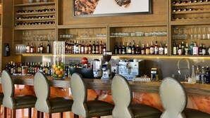 A bar area with a leopard print artwork, multiple shelves of bottles, and bar stools. - Safari Plains (Bela-Bela)