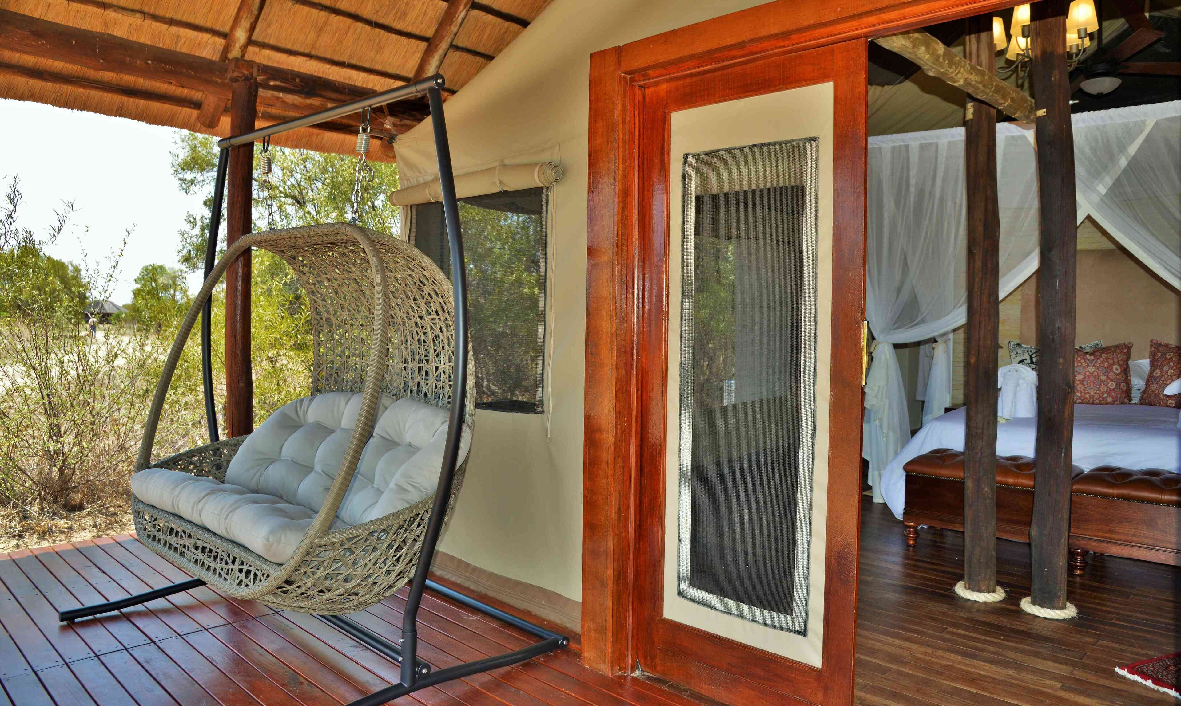 A wicker chair with a cushioned seat and back, positioned on a wooden deck.