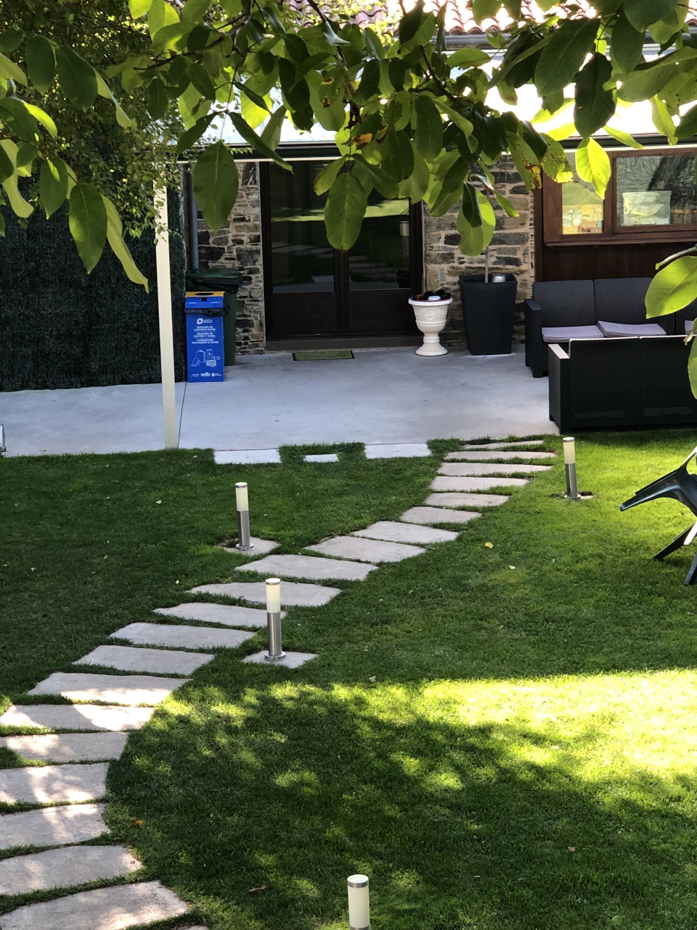 A stone pathway leading to a patio area with outdoor furniture and a stone wall.