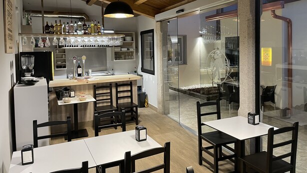 Un restaurante con zona de bar, techo de madera y disposición de asientos.