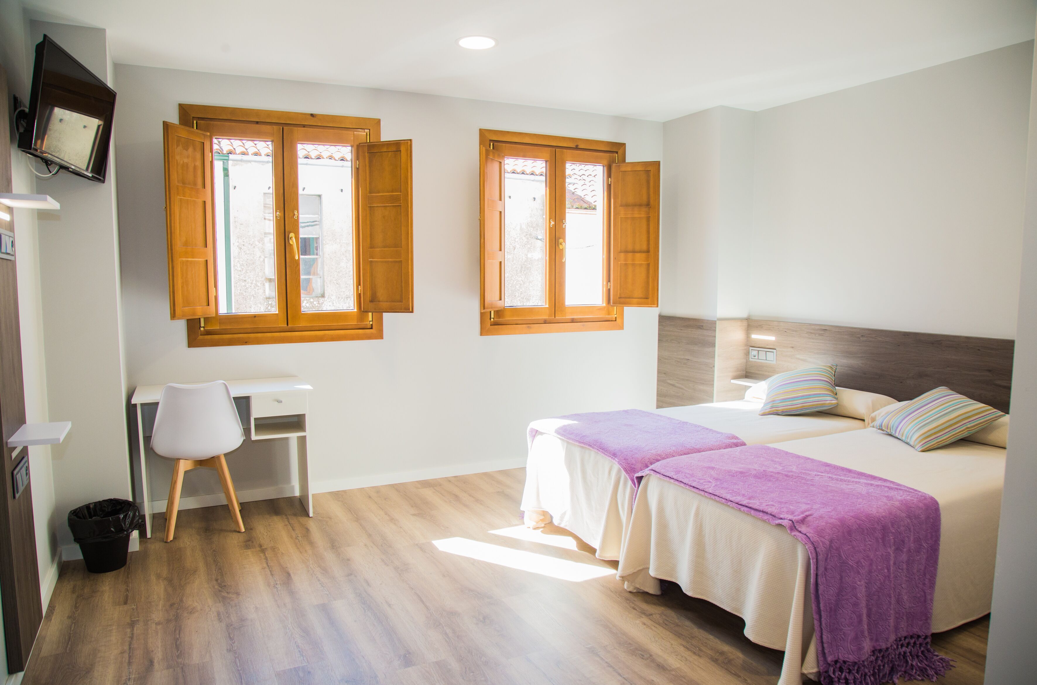 A bedroom with two beds, a desk, and a chair.