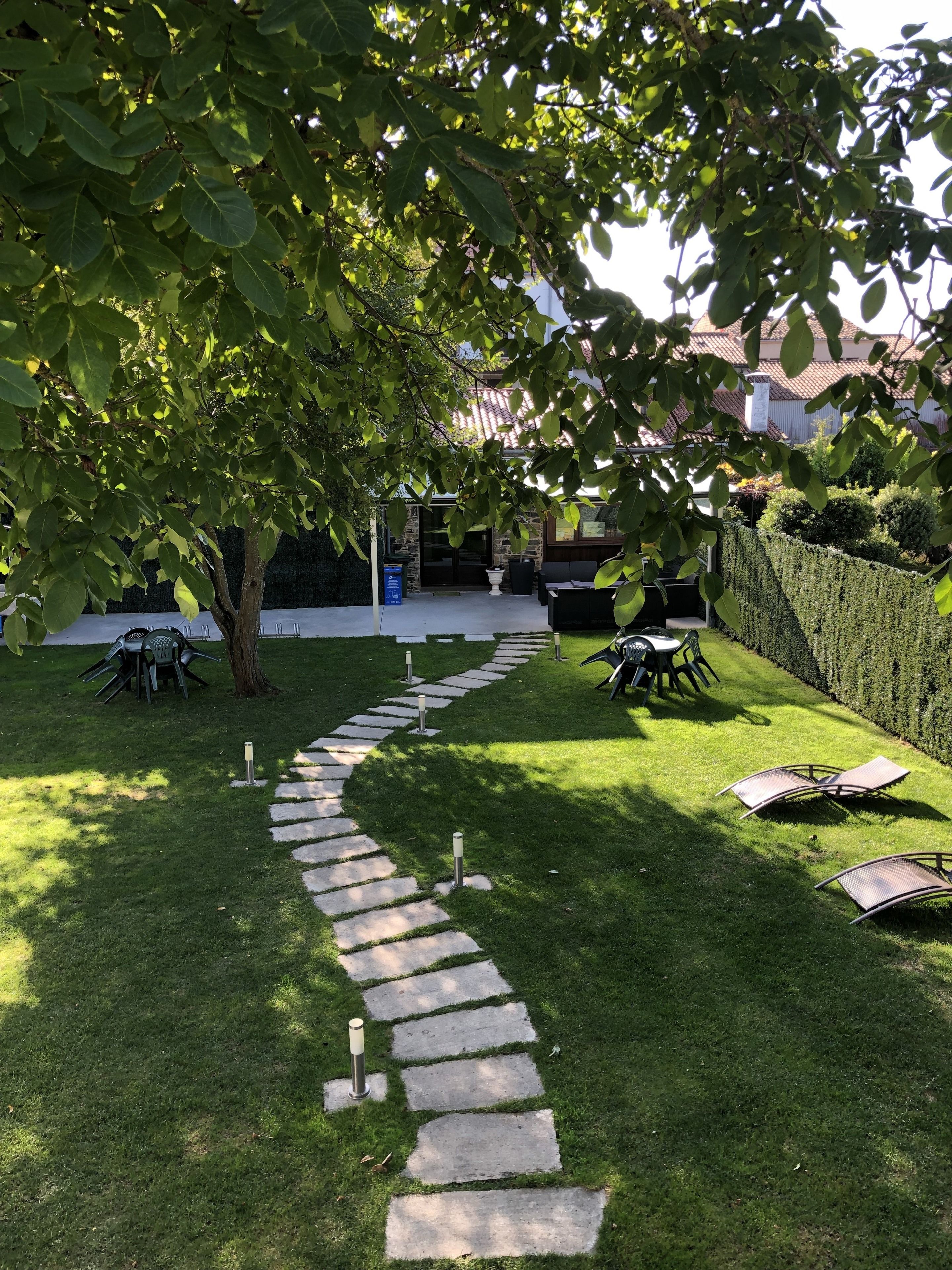 Een tuin met een pad van stenen dat leidt naar een zithoek met tuinmeubilair.