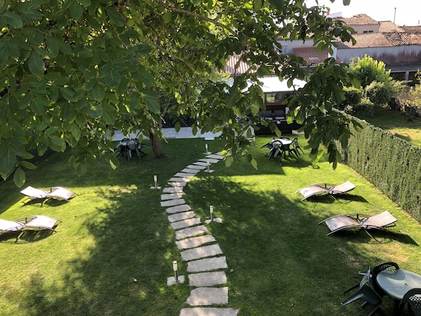 A garden with a stone pathway leading to a seating area with tables and chairs. - Pensión San Antón - Hostel (Melide)