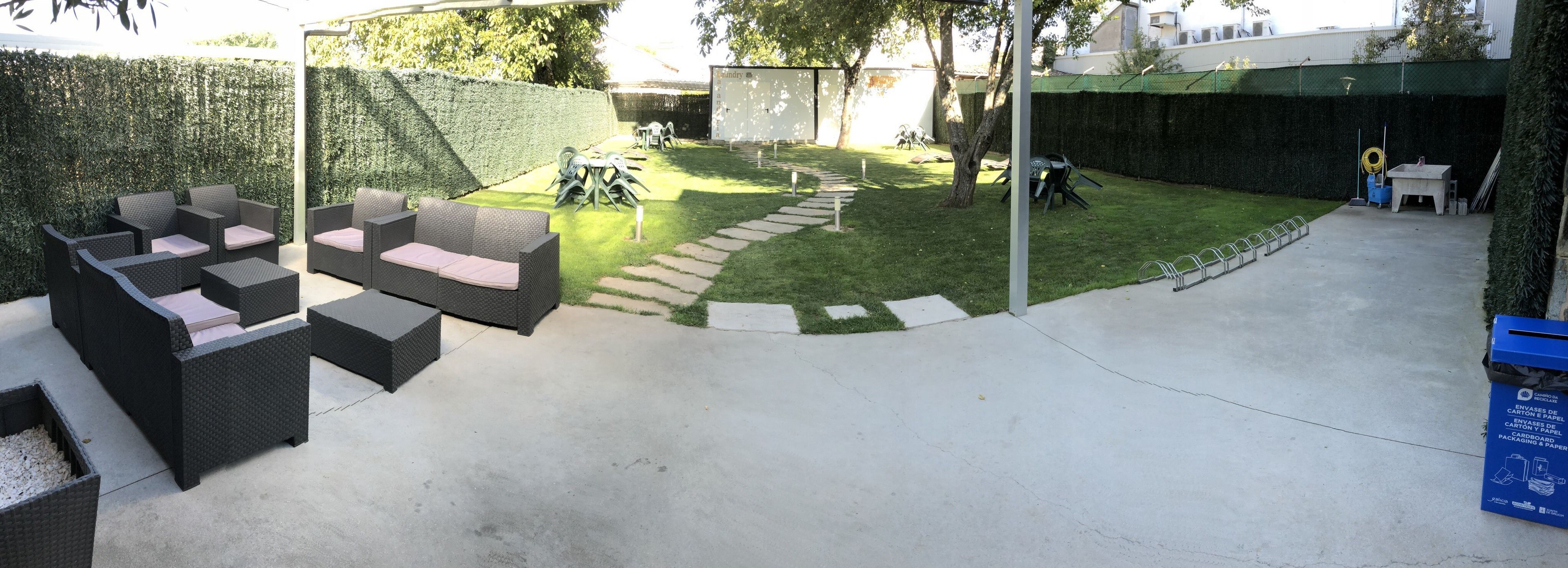 A patio area with outdoor furniture, a hedge, and a concrete path.