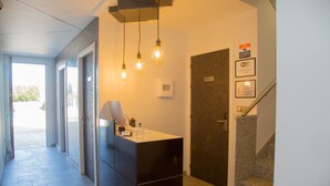 Un área de recepción moderna con un mostrador, un cartel que indica sala privada y una escalera.