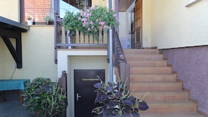 Una escalera conduce a una puerta con la leyenda "Fahrdgarage", con plantas en macetas y una mesa cerca.