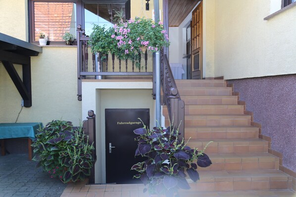 A staircase leading to a door labeled "Fahrdgarage," with potted plants and a table nearby.