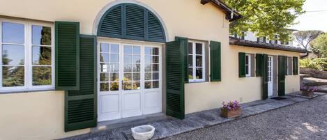 A building with a large arched window and multiple doors with green shutters.