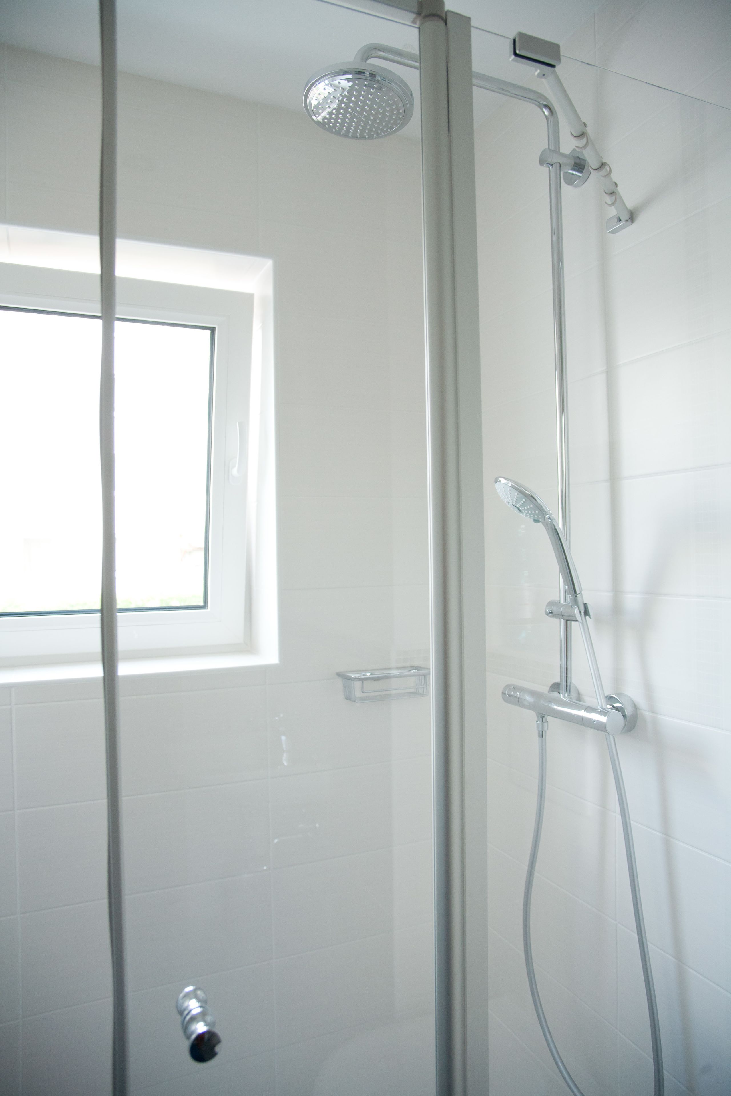 Een douche met een handdouche en een kraan op de muur.