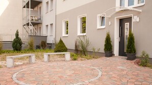 A courtyard with a circular brick pattern, potted plants, and a building entrance with a door and windows. - Apartmenthaus Wesertor (Kassel)