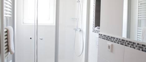 A modern bathroom with a glass-enclosed shower, a white sink, and a mirror with a decorative tile border.