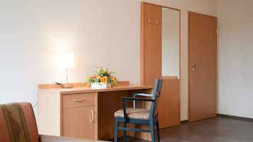 Une pièce avec un bureau en bois, une chaise, une lampe et un miroir.
