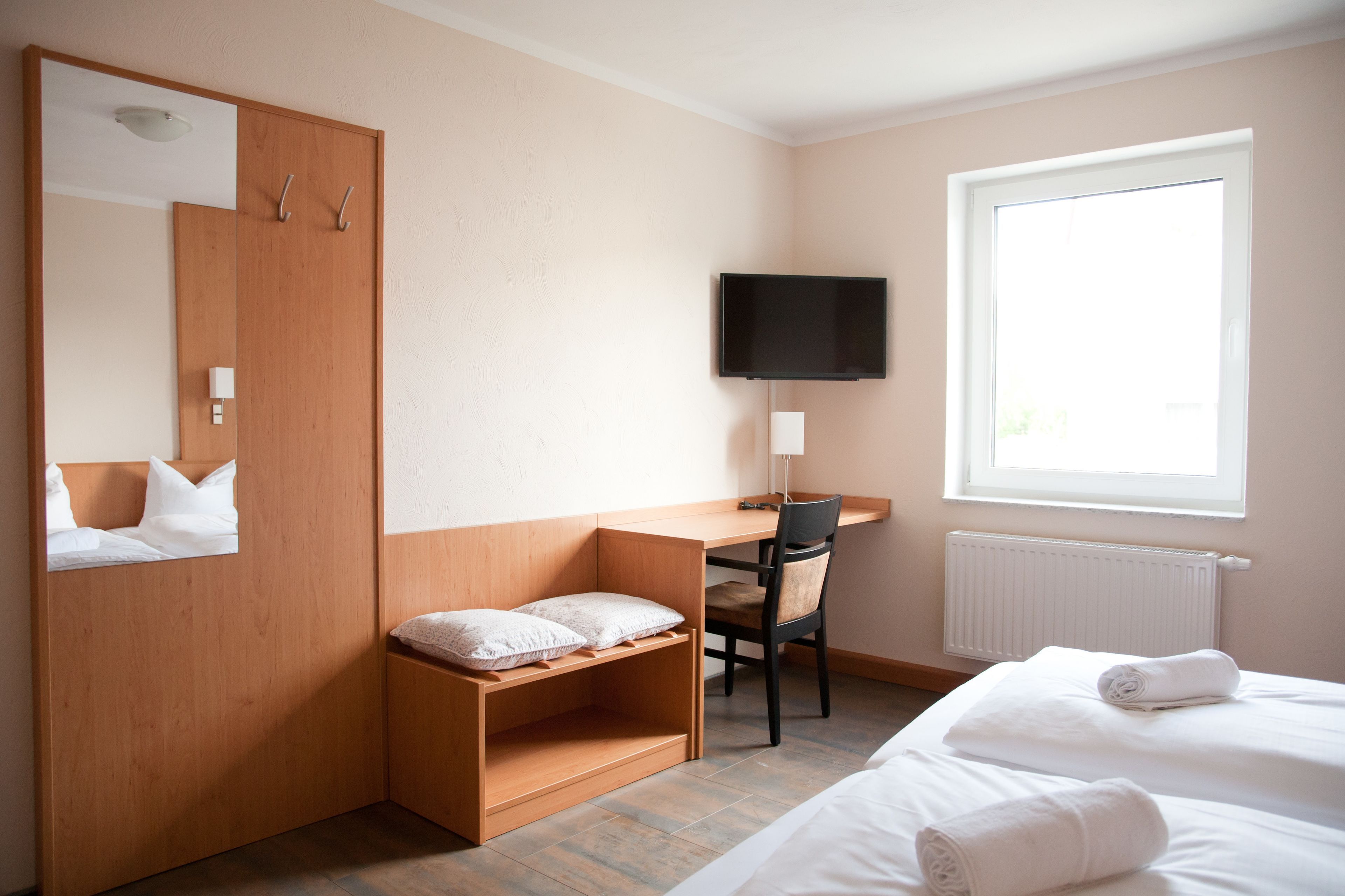 Una camera da letto con un letto, una scrivania, una sedia, una televisione e una finestra.