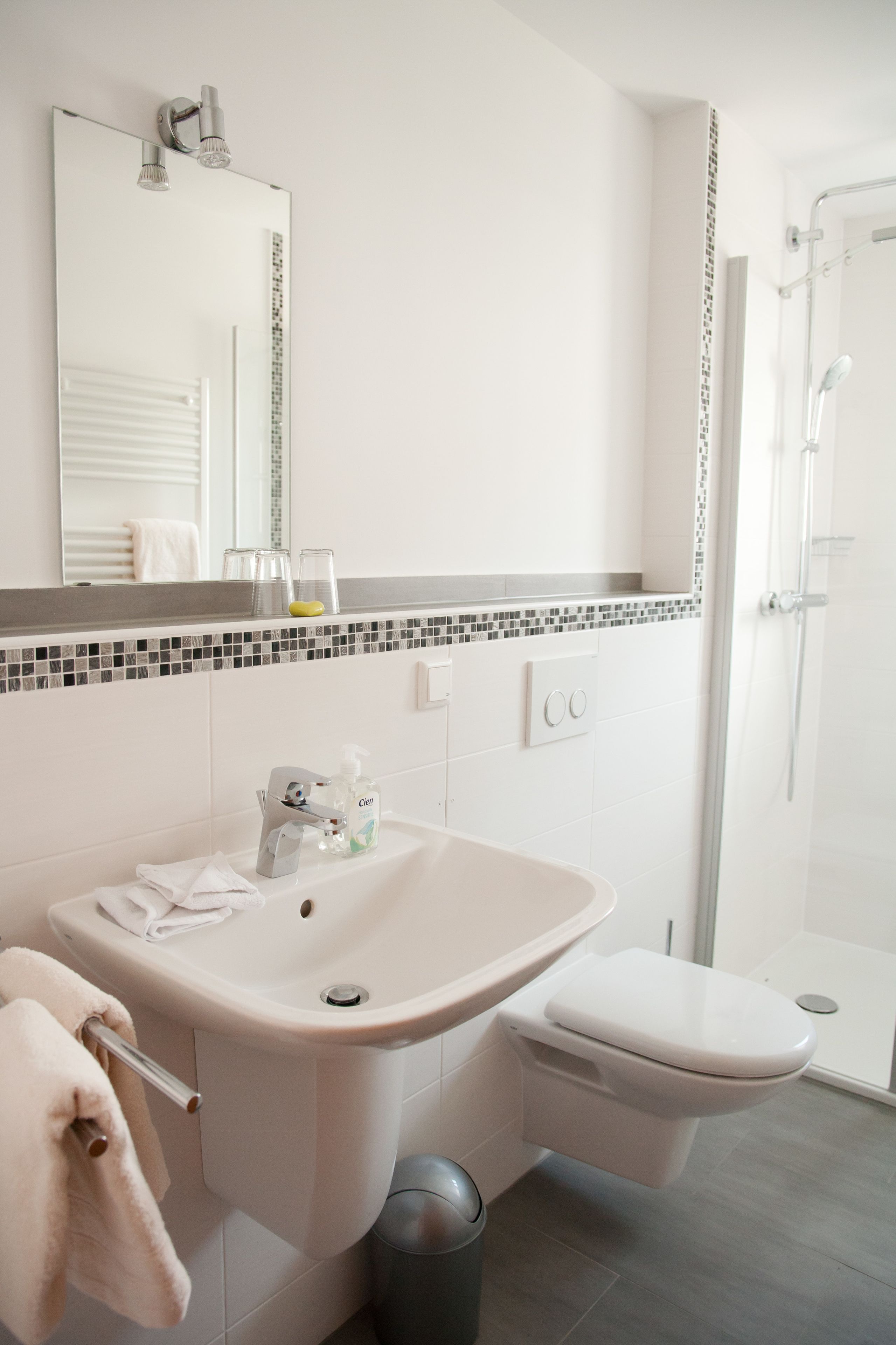 A modern bathroom with a white sink, toilet, and shower.