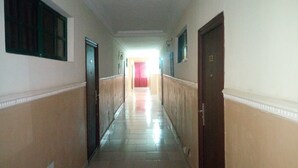 A long, narrow hallway with doors on both sides, leading to a brightly lit room at the end. - Abal Hall and Hotels (Ibadan)