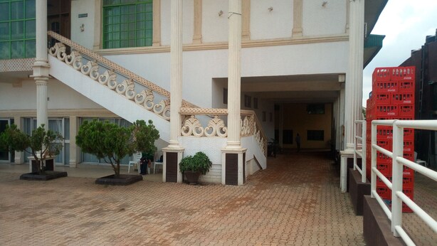 A building with a central staircase, potted plants, and a Coca-Cola crate. - Abal Hall and Hotels (Ibadan)