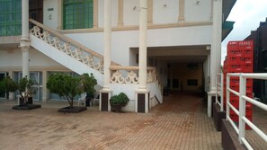 A building with a central staircase, potted plants, and a Coca-Cola crate. - Abal Hall and Hotels (Ibadan)
