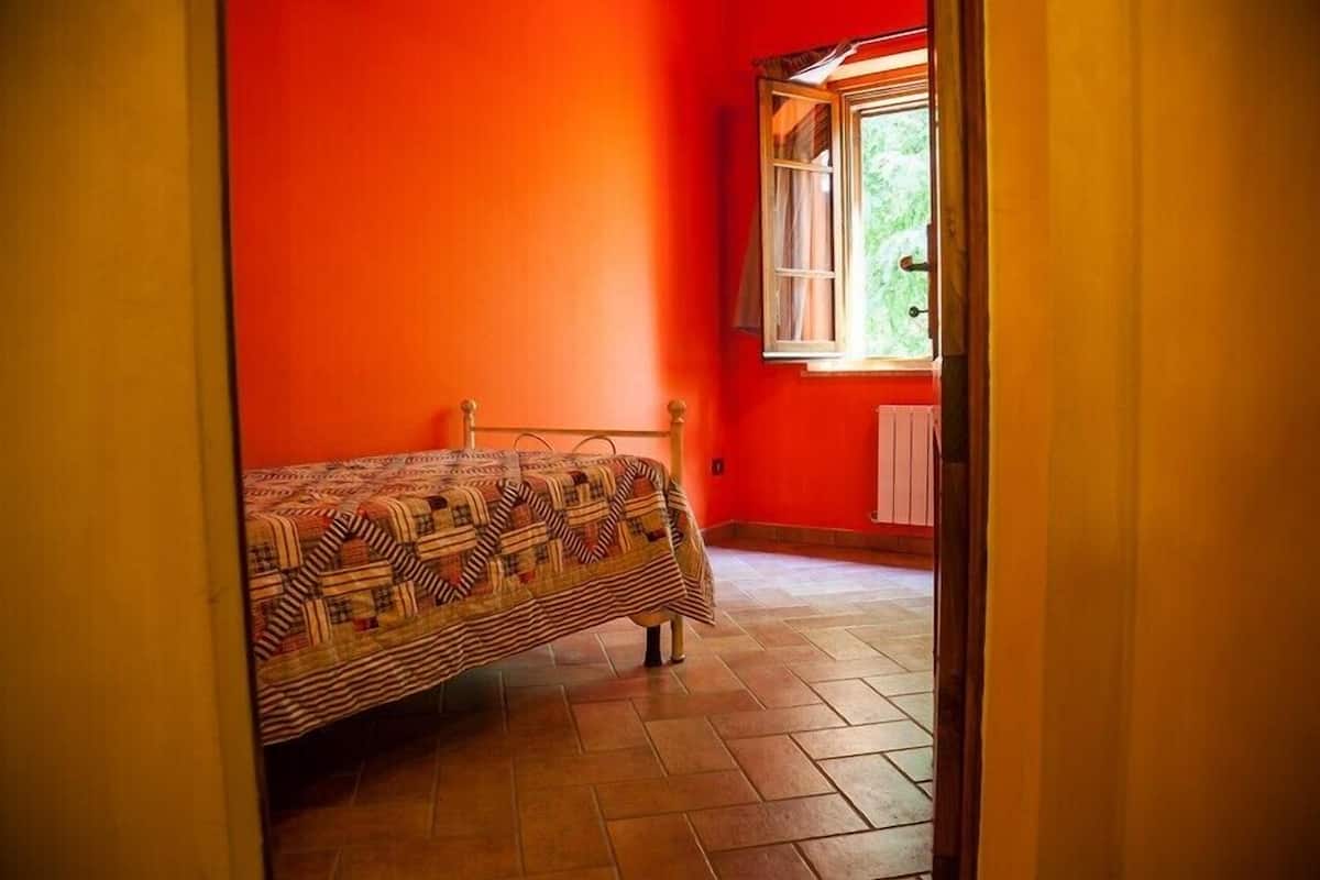 Une pièce avec un lit, une fenêtre et un radiateur.