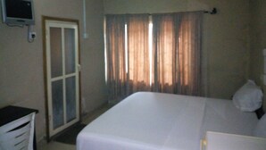 A room with a bed, a ceiling fan, an air conditioning unit, a door, and curtains. - Abeokuta Hill View Hotel (Abeokuta)