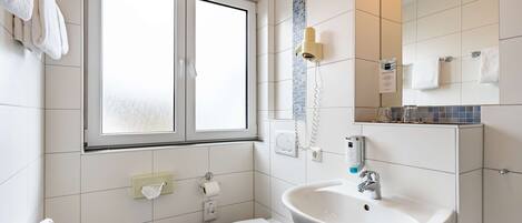 A modern bathroom with a toilet, sink, and window.