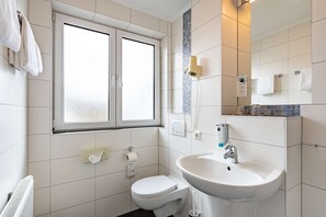 Ein modernes Badezimmer mit Toilette, Waschbecken und Fenster.