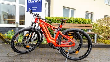 A red mountain bike parked in front of a building with a sign that reads "Dorint Parkhotel Siegen".