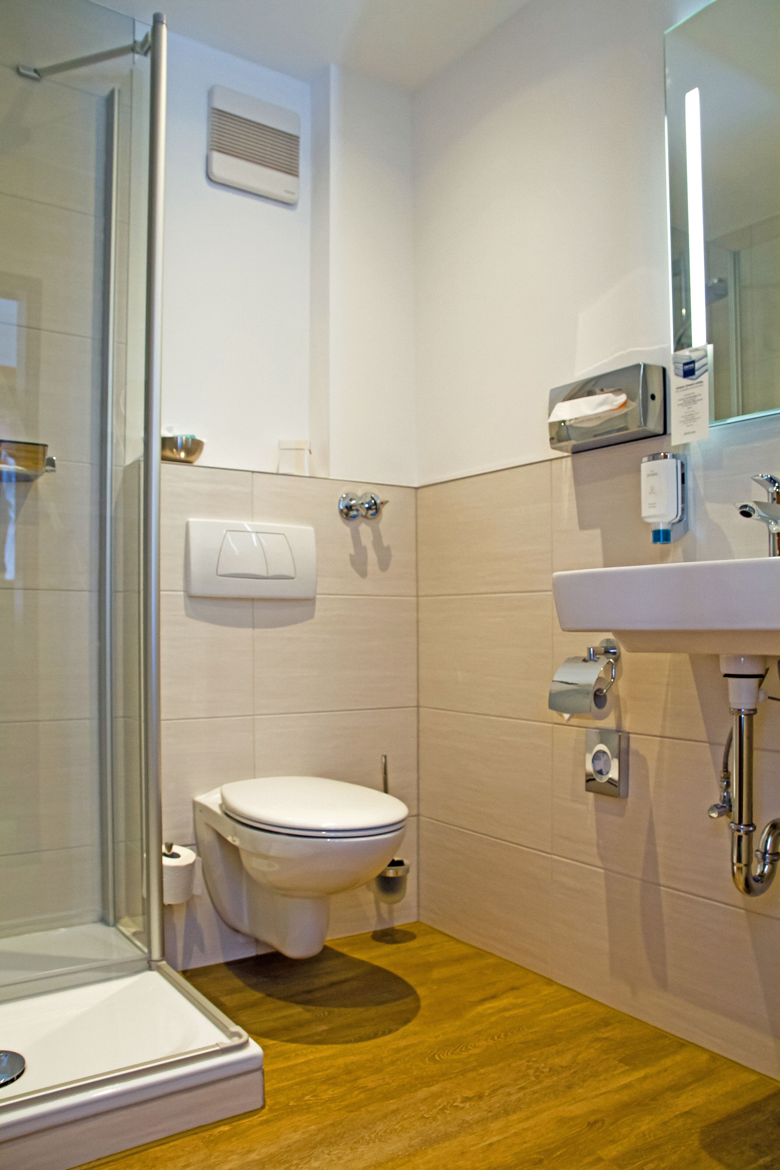 A modern bathroom with a glass shower enclosure, a toilet, and a sink with a mirror above it.