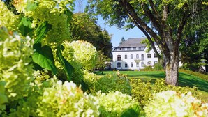 A large white building with multiple windows and a well-maintained garden with various plants and a lawn. - Dorint Parkhotel Siegen (Siegen)