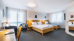 Ein Hotelzimmer mit Bett, Stuhl, Schreibtisch und Nachttisch.