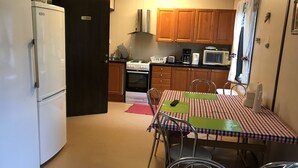 A compact kitchen with a refrigerator, stove, microwave, and wooden cabinets. - Rosenlund - Hostel (Fagersta)