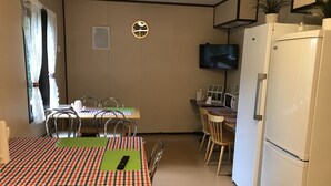 A compact kitchen with a dining table, chairs, a refrigerator, a microwave, and a TV. - Rosenlund - Hostel (Fagersta)