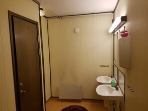 A compact bathroom with two sinks, a mirror, and a toilet.