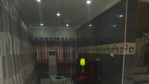 Um hall de hotel com piso de azulejos, um balcão de recepção, uma cadeira, um abajur e uma escada.