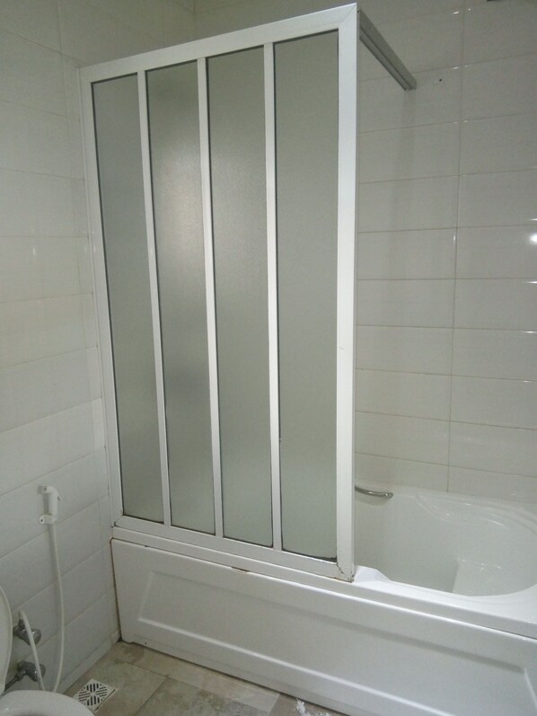 A bathroom with a bathtub, a toilet, and a shower enclosure.