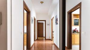 Un pasillo con puertas de madera, suelo de mármol y vistas a una zona de cocina.