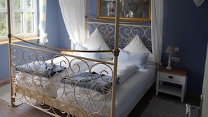 Un lit à baldaquin, une table de chevet avec une lampe et un miroir au mur.