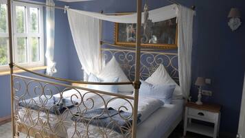 Ein Himmelbett mit Baldachin, ein Nachttisch mit Lampe und ein Spiegel an der Wand.