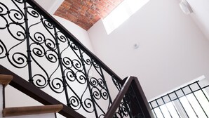 Un escalier avec des rampes en métal noir ouvragé et des marches en bois.