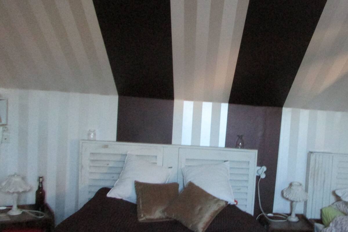 A bedroom with a bed, two nightstands, and a window.